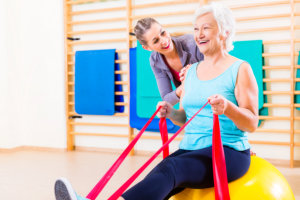 senior woman with stretch band in fitness gym